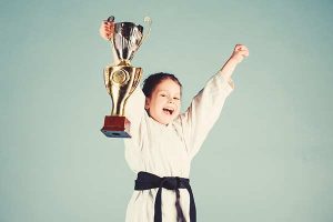 A kid martial artists holding a trophy